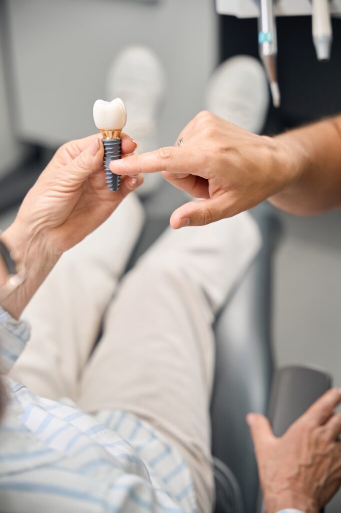 Female holds model of dental implant in hands